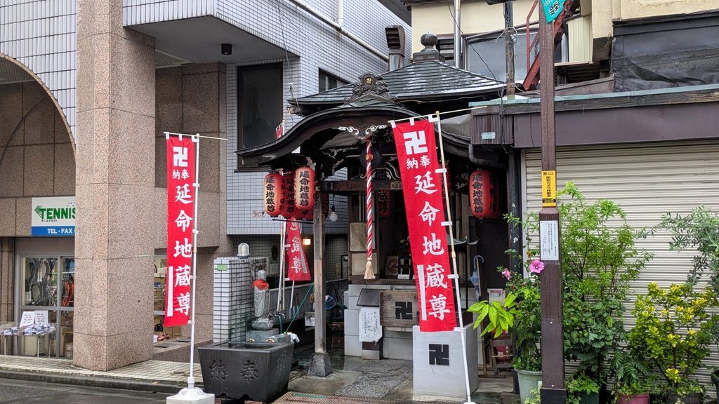 商店街を進むと、右手に小さなお堂の延命地蔵尊があります。赤い「延命地蔵尊」の幟が目印です。